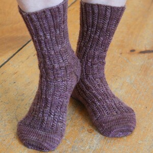 May include: A pair of purple knitted socks with a cable knit pattern.