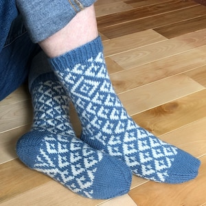 Pode incluir: Um par de meias azuis e brancas com um padrão geométrico. As meias são feitas de um tecido macio e de malha.