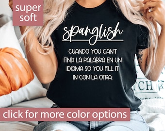 May include: Black t-shirt with white text that reads "Spanglish" and a definition in Spanish and English. The text says "Cuando you can't find la palabra en un idioma so you fill it in con la otra."