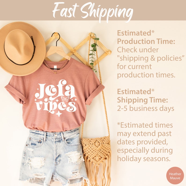 May include: A heather mauve t-shirt with the text "Jofa Vibes" in a retro font, featuring a butterfly graphic. The shirt is displayed with denim shorts, a straw hat, and a woven bag.