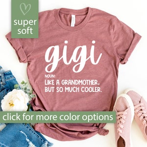 May include: A maroon t-shirt with the word "gigi" written in white cursive lettering. The text "NOUN: LIKE A GRANDMOTHER, BUT SO MUCH COOLER." is written in white below the word "gigi".