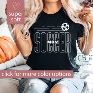 Pu&ograve; includere: Maglietta nera con testo bianco che dice "Soccer Mom" e un pallone da calcio con un cuore.