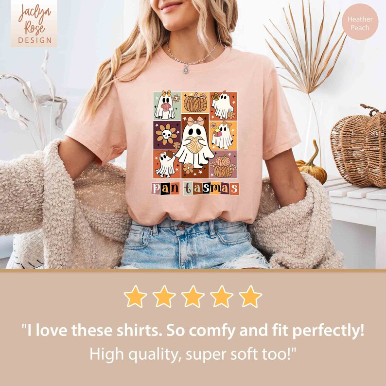 K&ouml;nnte beinhalten: Ein pinkfarbenes T-Shirt mit einem grafischen Design aus Geistern und K&uuml;rbissen, die in einem Raster angeordnet sind. Der Text "Pantasmas" ist unter dem Design gedruckt.
