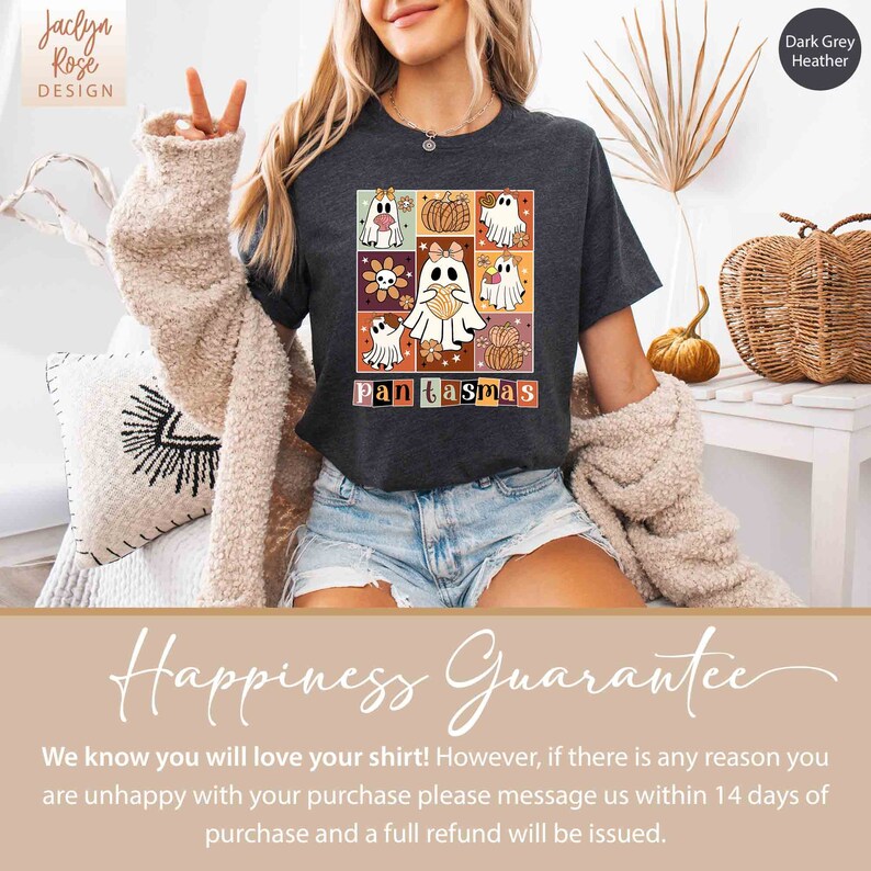 K&ouml;nnte beinhalten: Ein dunkelgraues T-Shirt mit einem Grafikdruck eines Geistes, der ein Herz h&auml;lt, mit dem Text "Pantasmas" darunter. Die Grafik ist von einem bunten Muster aus Blumen, K&uuml;rbissen und anderen Herbstmotiven umgeben.
