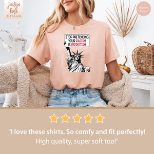 Peut inclure: Un t-shirt couleur p&ecirc;che avec un graphique de la Statue de la Libert&eacute; tenant une pancarte qui dit "Stop Pretending Your Racism Is Patriotism".