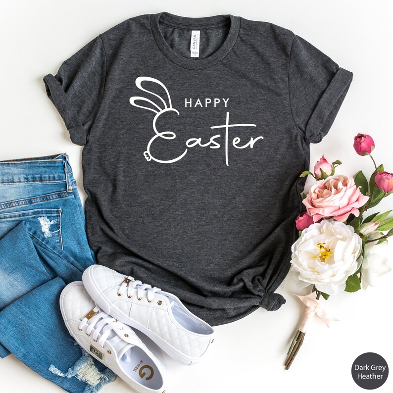 May include: A dark grey heather t-shirt with a white bunny ear design and the text "Happy Easter".