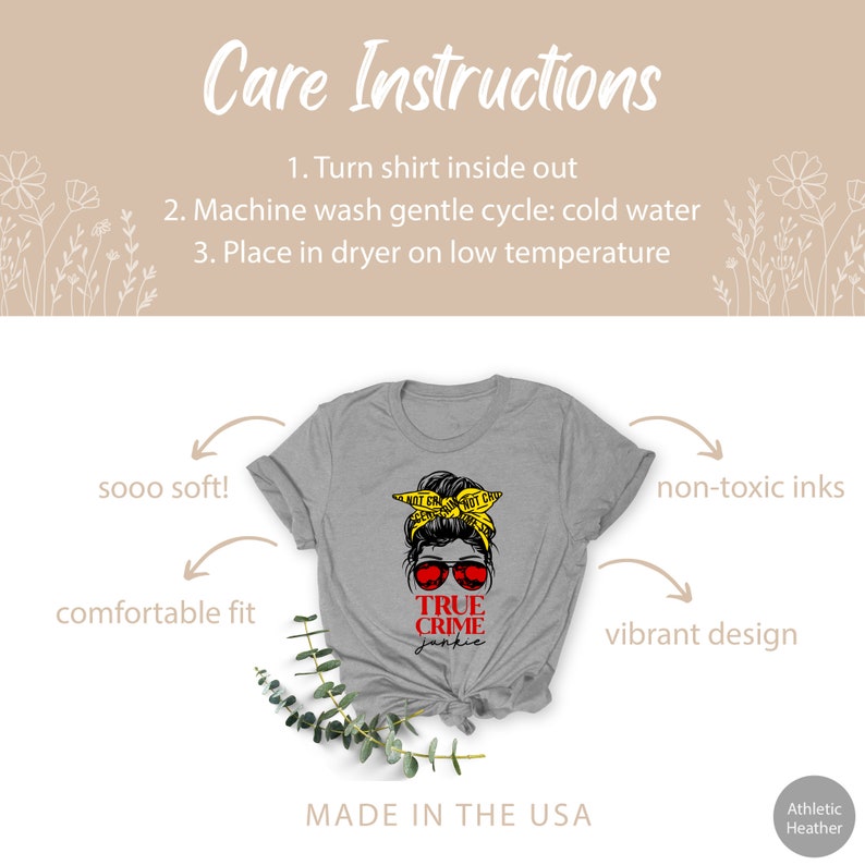 May include: Gray t-shirt with a graphic of a woman with a messy bun wearing sunglasses and a yellow "Do Not Cross" tape headband. The text "TRUE CRIME JUNKIE" is printed in red below the graphic. The shirt is made in the USA.