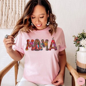May include: Pink t-shirt with a colorful "MOMA" graphic featuring a religious figure in the center of the "O".