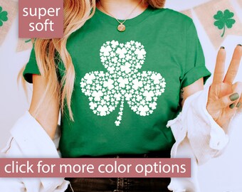 Könnte beinhalten: Ein grünes T-Shirt mit einem weißen Kleeblatt-Design aus kleineren Kleeblättern. Der Text "super soft" befindet sich in der oberen linken Ecke des Bildes. Der Text "Klicke für weitere Farboptionen" befindet sich unten im Bild.