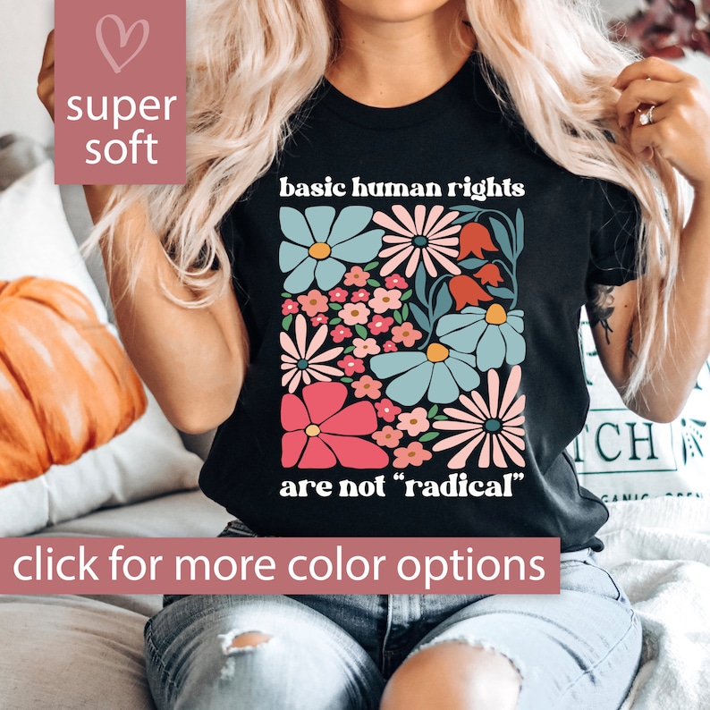 May include: Black t-shirt with a floral design and the text "basic human rights are not "radical""