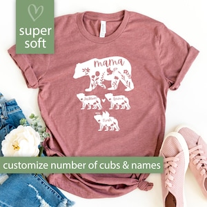 May include: A maroon t-shirt with a white floral design of a mama bear and three cubs. The text "mama" is above the bear and the cubs are labeled "Jackson", "Emma", and "Noah".
