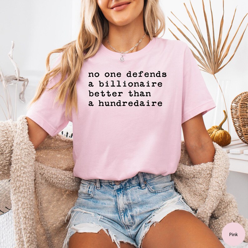 K&ouml;nnte beinhalten: Rosa T-Shirt mit dem Text "no one defends a billionaire better than a hundredaire" in Schwarz gedruckt.