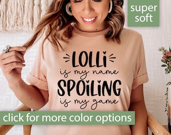 May include: A peach-colored t-shirt with black text that reads "LOLLI is my name SPOILING is my game". The text is in a playful, handwritten font. The t-shirt is super soft.