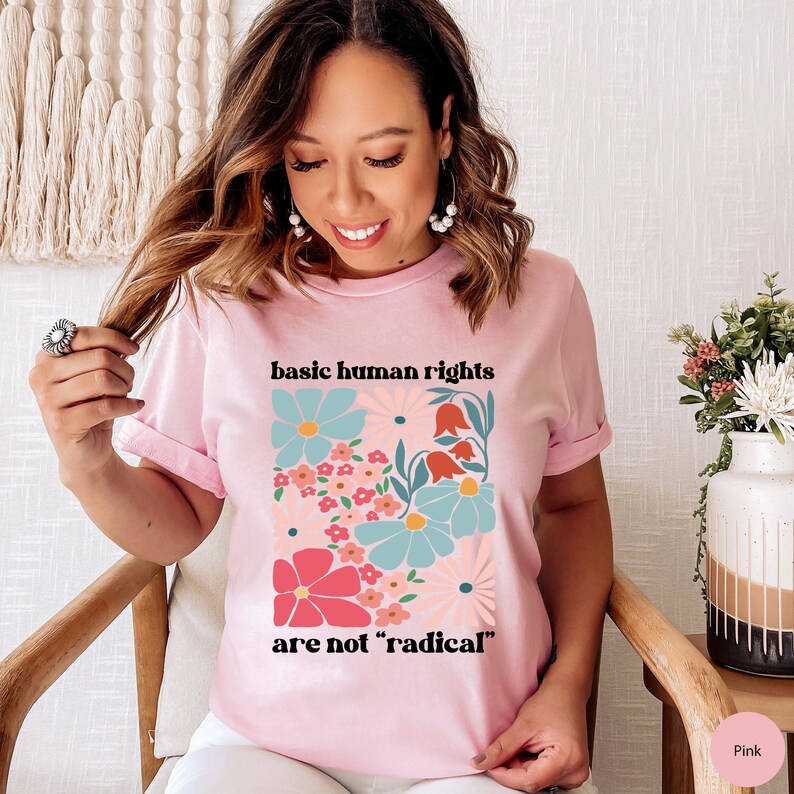 May include: Pink t-shirt with a floral design and the text "basic human rights are not 'radical'"