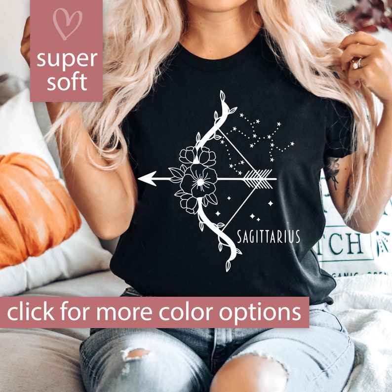May include: Black t-shirt featuring a white floral design of an arrow and bow with the text "Sagittarius" underneath.