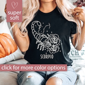Pu&ograve; includere: Maglietta nera con un contorno bianco di uno scorpione con fiori e la parola "Scorpio" stampata sul davanti.