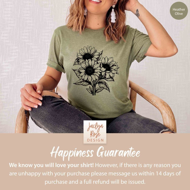 May include: Heather olive-colored t-shirt featuring a black and white sunflower bouquet design. The shirt includes the text "Jaclyn Rose Design" and "Happiness Guarantee". The shirt is made of a soft material.