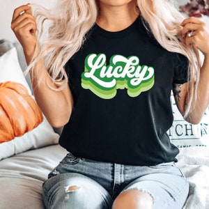 May include: A black t-shirt with a green and white retro-style graphic that says "Lucky".