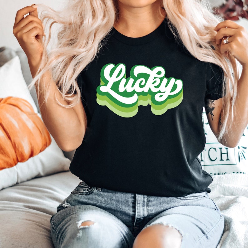 May include: A black t-shirt with a green and white retro-style graphic that says "Lucky".