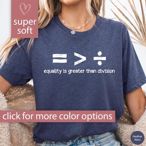 May include: A navy blue t-shirt with a white graphic of an equals sign, a greater than sign, and a division sign. The text "equality is greater than division" is printed below the graphic.