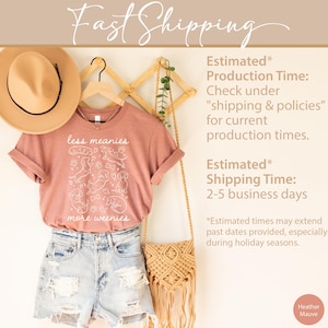Op de afbeelding: Heather mauve t-shirt met de tekst "less meanies more weenies" en een afbeelding van teckels. Het shirt wordt gecombineerd met een spijkerbroek, een strohoed en een macram&eacute; tas. De tekst "Fast Shipping" staat bovenaan.