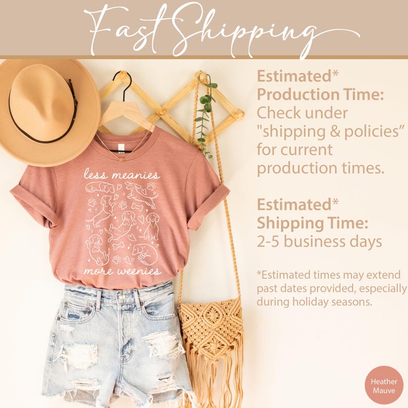 Op de afbeelding: Heather mauve t-shirt met de tekst "less meanies more weenies" en een afbeelding van teckels. Het shirt wordt gecombineerd met een spijkerbroek, een strohoed en een macram&eacute; tas. De tekst "Fast Shipping" staat bovenaan.