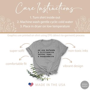 K&ouml;nnte beinhalten: Ein heidefarbenes T-Shirt mit dem Aufdruck "no one defends a billionaire better than a hundredaire". Das Shirt ist in den USA hergestellt und bietet eine bequeme Passform, superweiches Material, ungiftige Tinten und ein lebendiges Design.