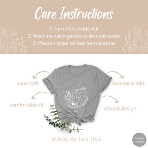 May include: Gray t-shirt with a white outline of a lion and constellation with the word "Leo" underneath. The shirt is made in the USA and features a comfortable fit, non-toxic inks, and a vibrant design. Care instructions are listed above the shirt.