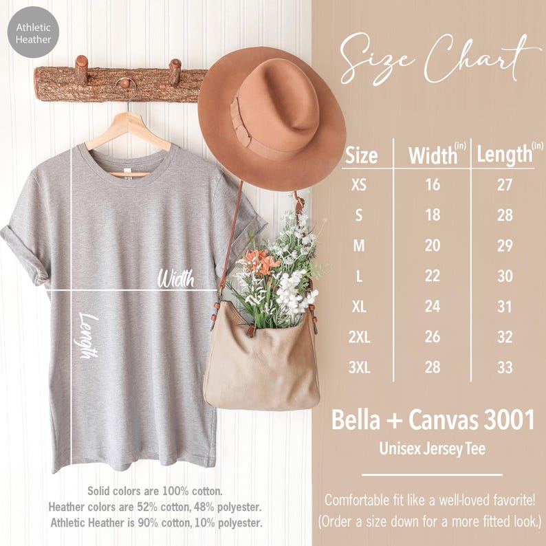 May include: A size chart for a unisex jersey tee, showing the width and length measurements in inches for sizes XS to 3XL. The chart is printed on a light brown background with a gray t-shirt hanging on a wooden rack.