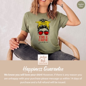 May include: A green t-shirt with a graphic of a woman with a messy bun and sunglasses. The text "TRUE CRIME junkie" is printed on the shirt. The shirt is available in Heather Olive.