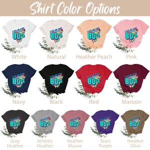 Pu&ograve; includere: Un mockup di diversi colori di magliette con un design grafico che dice "Take Me Back To The 80's" con un font e un design in stile retr&ograve; degli anni '80.