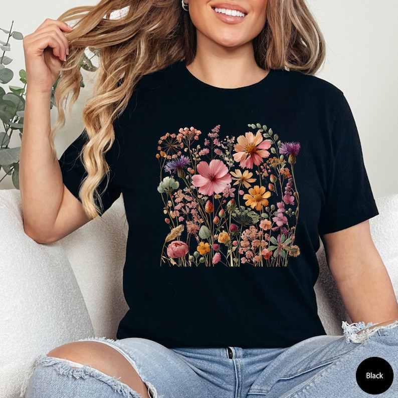 K&ouml;nnte beinhalten: Schwarzes T-Shirt mit einem Blumendruck mit verschiedenen rosa, orangefarbenen und gelben Blumen.