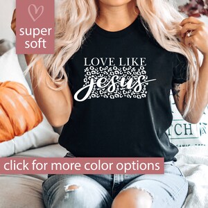 Pode incluir: Camiseta preta com texto branco que diz "Love Like Jesus" com um design de estampa de leopardo atr&aacute;s do texto.