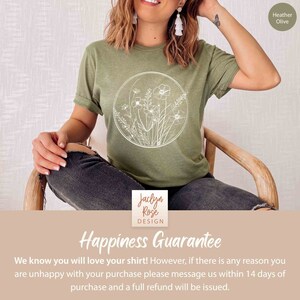May include: A green t-shirt with a white outline of flowers and leaves in a circle. The text "Jaclyn Rose DESIGN" is on the bottom of the shirt. The text "Happiness Guarantee" is on a tan background with the text "We know you will love your shirt! However, if there is any reason you are unhappy with your purchase please message us within 14 days of purchase and a full refund will be issued." below it.