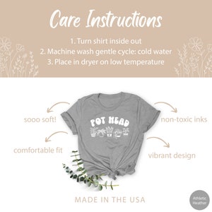 May include: A gray t-shirt with the text "POT HEAD" in white lettering. The shirt has a graphic of potted plants. The text "sooo soft!" and "comfortable fit" are written on the left side of the image. The text "non-toxic inks" and "vibrant design" are written on the right side of the image. The text "MADE IN THE USA" is written at the bottom of the image.