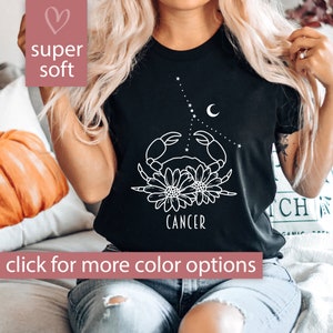 May include: Black t-shirt with a white outline of a crab, flowers, and the word "Cancer".
