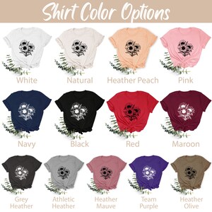 May include: A selection of t-shirts in various colors, including white, navy, and black. Each shirt features a black and white floral design. The text "Shirt Color Options" is at the top of the image.