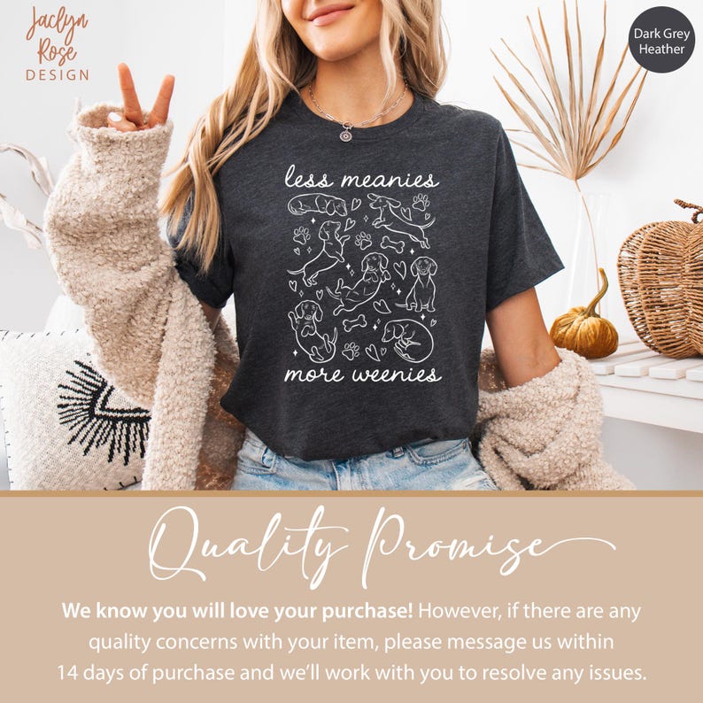 Op de afbeelding: Donkergrijze heather t-shirt met de tekst "less meanies more weenies" en een witte afbeelding van teckels, harten en pootafdrukken. Het t-shirt heeft een ronde hals en korte mouwen.