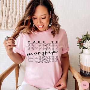 May include: Pink t-shirt with the text "MADE TO WORSHIP worship WORSHIP PSALM 95:1" printed in black.