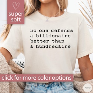 K&ouml;nnte beinhalten: Ein wei&szlig;es T-Shirt mit dem Text "no one defends a billionaire better than a hundredaire" in Schwarz gedruckt. Das Shirt ist super weich und hat eine lockere Passform.