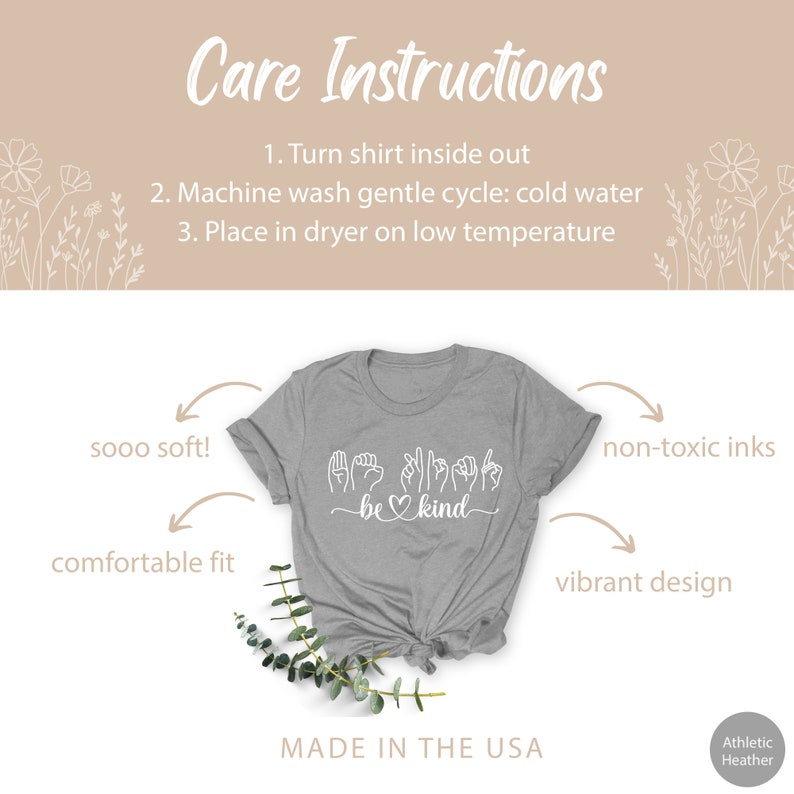 May include: Gray t-shirt with a white design that says "be kind" in sign language. The shirt is made in the USA and is made with non-toxic inks. The shirt is soft and comfortable.