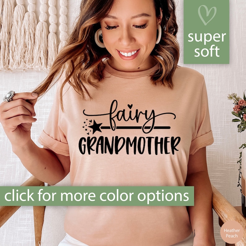 K&ouml;nnte beinhalten: Ein hellrosa T-Shirt mit dem Text "fairy grandmother" in schwarzer Schrift. Der Text ist in einer kursiven Schrift mit einem Stern und einer Linie darunter geschrieben. Das Shirt ist super weich.