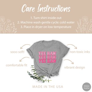 May include: Gray t-shirt with the phrase "Yee Haw" repeated three times in pink lettering. The shirt is made in the USA and features a comfortable fit, soft fabric, and non-toxic inks.