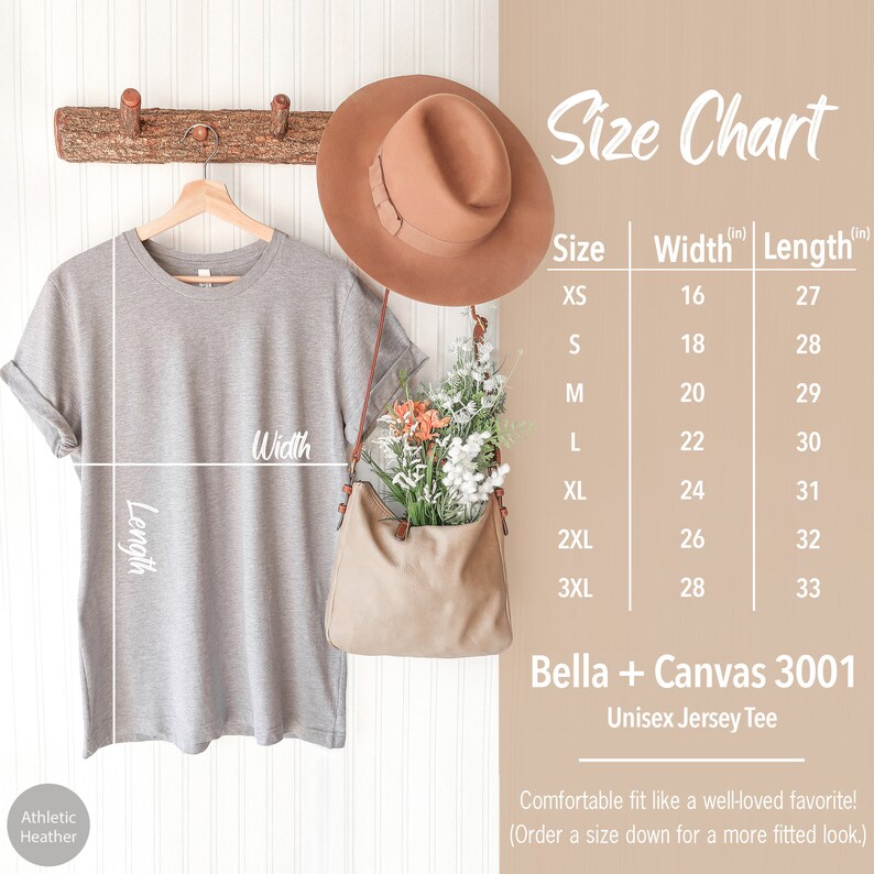 May include: A size chart for a unisex jersey tee, showing the width and length measurements in inches for sizes XS to 3XL. The chart is printed on a white background with a gray t-shirt hanging on a wooden rack above it. The t-shirt is gray and has the words "Athletic Heather" printed on the bottom left corner.