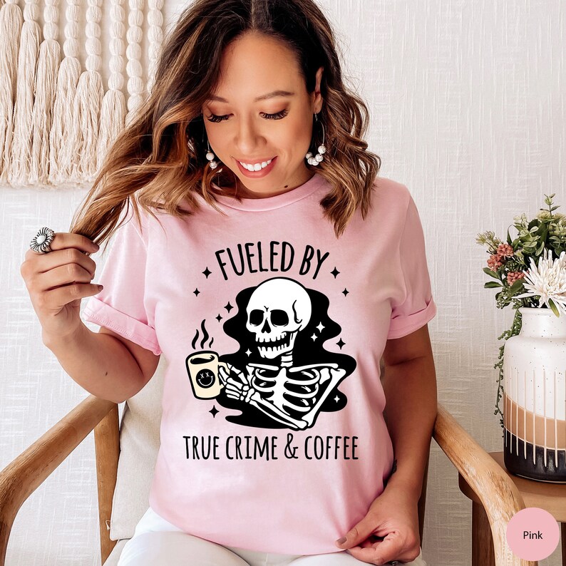 May include: Pink t-shirt with a black skeleton holding a coffee cup and the text "Fueled by True Crime & Coffee".
