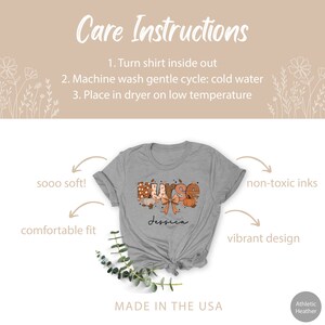 May include: A gray t-shirt with the word "Nurse" in orange, brown, and white letters with a pumpkin and bow design. The text "Jessica" is printed below the word "Nurse". The shirt is made in the USA and is described as being soft, comfortable, and having a vibrant design. The care instructions are to turn the shirt inside out, machine wash on a gentle cycle with cold water, and dry on low heat.