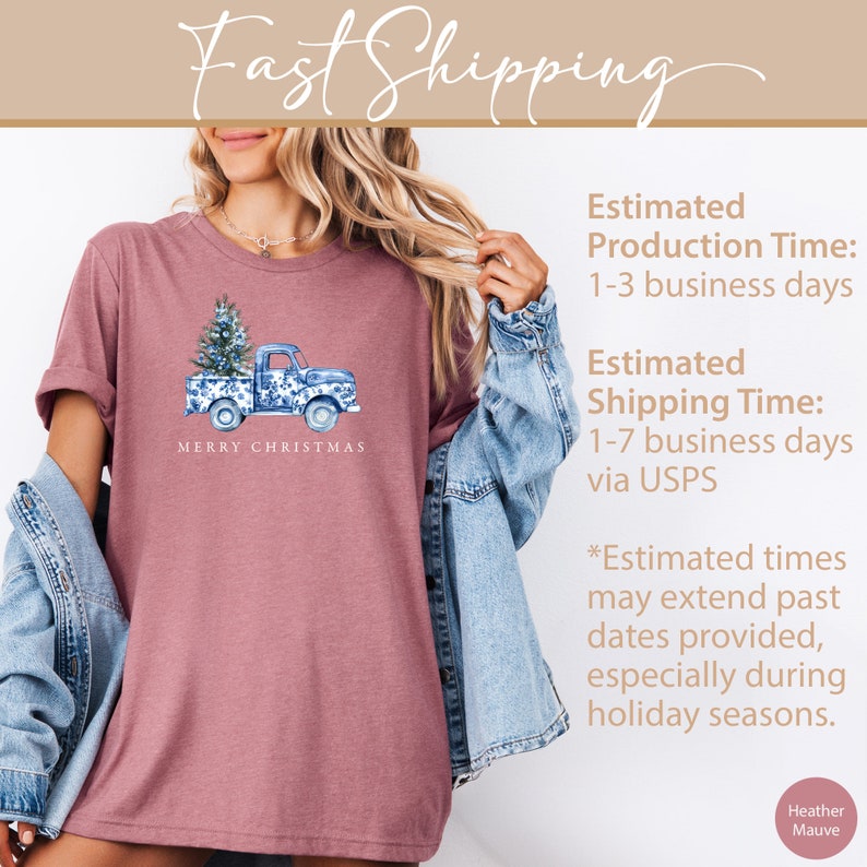 May include: A heather mauve t-shirt with a blue and white design of a pickup truck carrying a Christmas tree. The text "Merry Christmas" is printed below the truck.