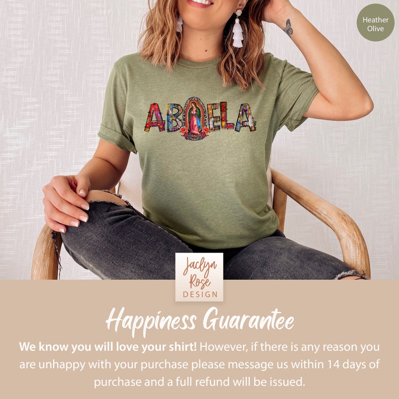 May include: A green t-shirt with the word "ABUELA" spelled out in colorful mosaic letters. The letters are decorated with images of religious figures and flowers. The shirt is being modeled by a person.