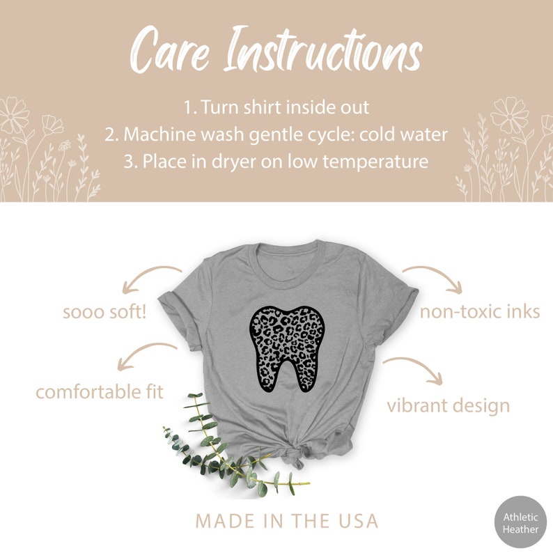 May include: A gray t-shirt with a black leopard print tooth graphic. The shirt is made of a soft, comfortable material and features a vibrant design. The text "sooo soft!" and "comfortable fit" are written on the left side of the image. The text "non-toxic inks" and "vibrant design" are written on the right side of the image. The text "Care Instructions" is written at the top of the image. The text "Made in the USA" is written at the bottom of the image. The text "Athletic Heather" is written in the bottom right corner of the image.