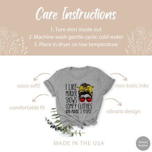 May include: Gray t-shirt with a black graphic of a woman with a messy bun and sunglasses. The text on the shirt reads "I like murder shows comfy clothes and maybe 3 people". The shirt is made in the USA.